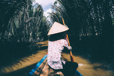 Rear view of person rowing boat in river