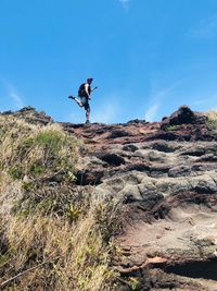 Man climbing rock on land against sky