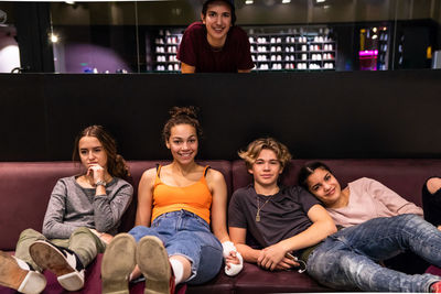 Portrait of multi-ethnic teenage friends on sofa at bowling alley