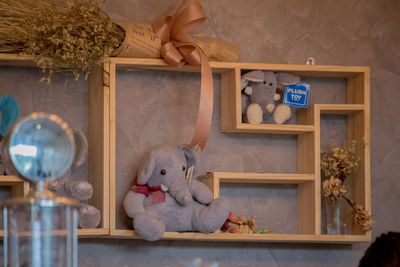 Toys and flowers on shelves against wall