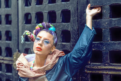 Portrait of fashionable young woman standing by wall