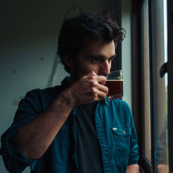 Man drinking tea while looking through window