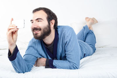 Portrait of man using mobile phone on bed