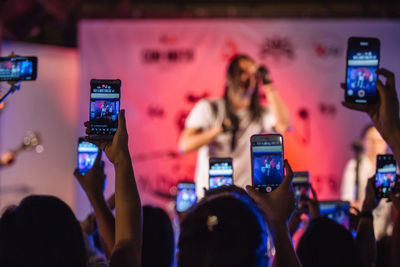 Rear view of people photographing at music concert