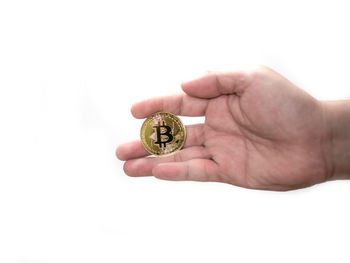 Close-up of hand holding ring over white background
