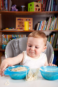 Cute baby boy with food on table at home