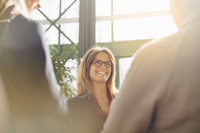 Smiling mature businesswoman discussing with colleagues in meeting