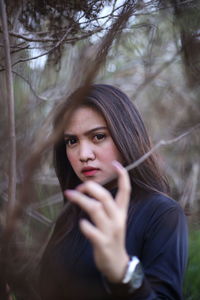 Portrait of beautiful young woman against trees