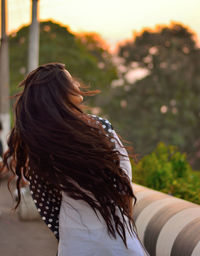 Midsection of woman with arms raised at sunset