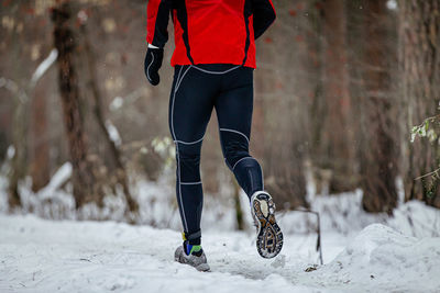 Low section of man skiing on snow covered field