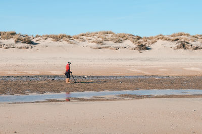 Rear view of man walking on beach against sky