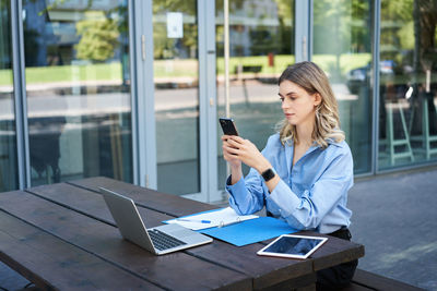 Businesswoman using mobile phone while sitting on table
