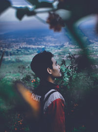 Side view of young man standing against landscape