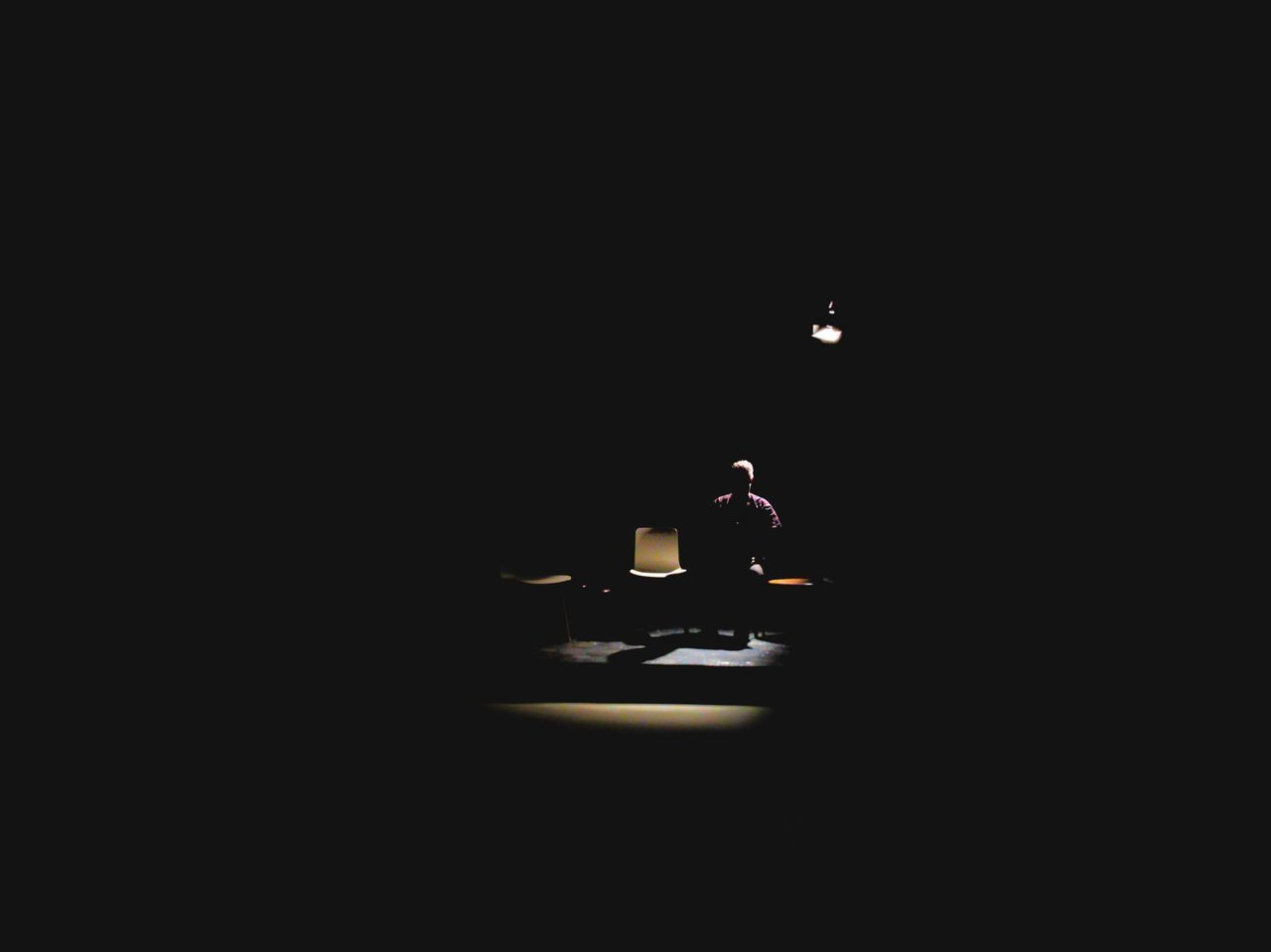 MAN SITTING ON ILLUMINATED TABLE