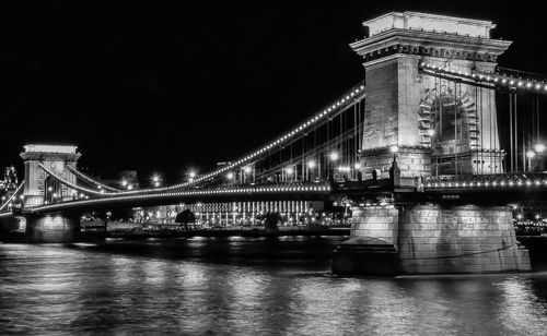 Illuminated bridge over river at night