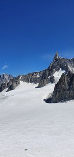 Scenic view of snowcapped mountains against clear blue sky