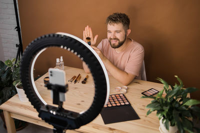 Side view of man using mobile phone while sitting on table