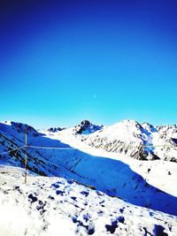 Scenic view of snow covered mountains against blue sky