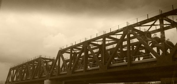 Low angle view of metal structure against cloudy sky