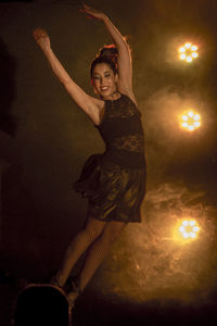 Young woman dancing on illuminated stage