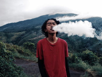 Young man standing on mountain against trees