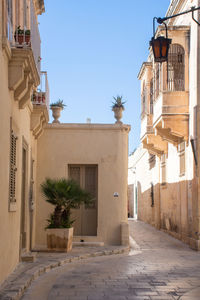 Alley amidst buildings in city against clear blue sky