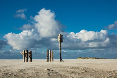 Lifeguard hut on sand against blue sky