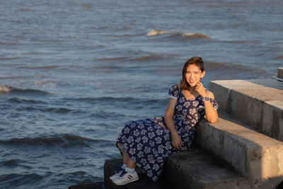 Side view of woman sitting at beach