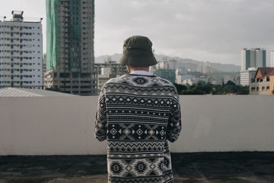 Rear view of man standing on terrace against buildings