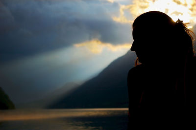 Silhouette woman against mountains at sunset