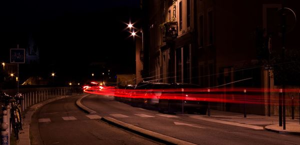 Light trails on city street by buildings at night