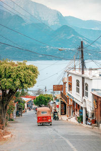 Cars on road by city against mountain