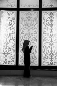 Side view of silhouette woman standing against window