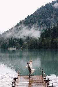 A happy couple in love and married embrace in nature by the lake and the misty mountains