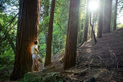 A teenage girl takes photos with her camera in the forest