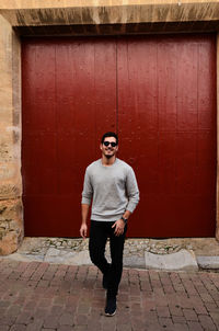 Portrait of young man standing against wall