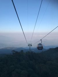 Overhead cable cars over landscape against sky