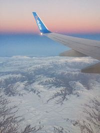 Aerial view of airplane wing over landscape against sky