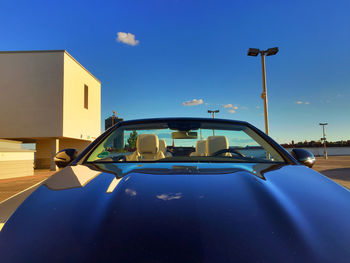 Car on road by building against blue sky