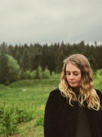 Beautiful young woman against trees and sky