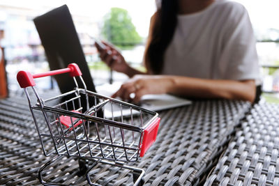 Midsection of woman doing online shopping with cart in foreground