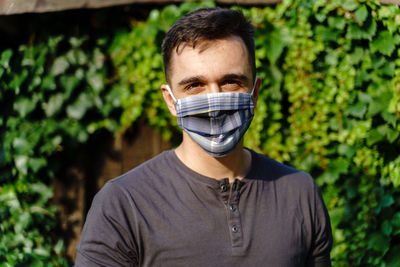 Portrait of young man standing against plants