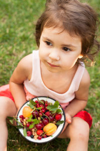 High angle view of baby girl sitting on grass