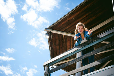 Low angle view portrait of woman standing at observation point against sky