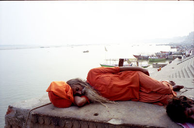 Man sleeping on beach against clear sky