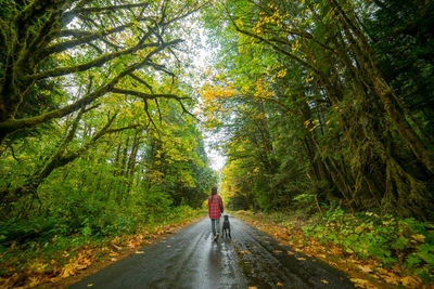 Young woman walking with dog on a road in dense forest