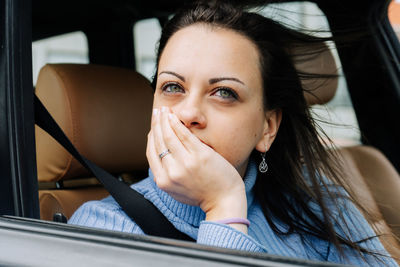 Portrait of a young woman sitting on the passenger seat of a car