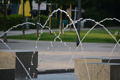 Water spraying from fountain by footpath