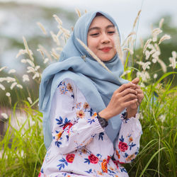Beautiful young woman with flowers on field