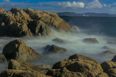 Scenic view of rocks in sea against sky